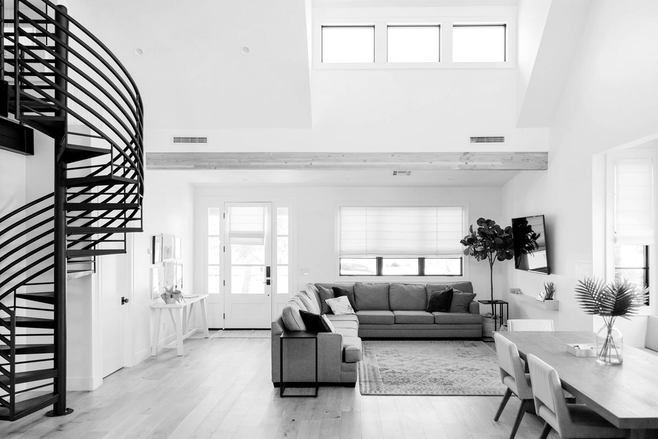 a black and white photo of a living room with a spiral staircase